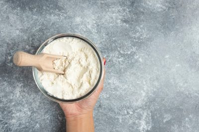 woman-hand-holding-glass-bowl-flour-marble_114579-31396